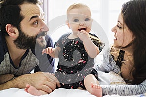 Happy family, mother, father and baby on the white bed