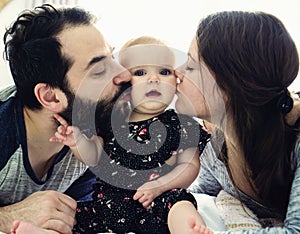 Happy family, mother, father and baby on the white bed