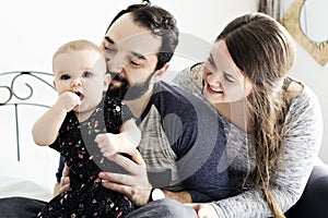 Happy family, mother, father and baby on the white bed