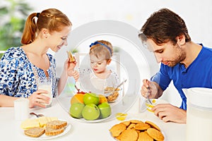 Happy family mother, father, child baby daughter having breakfast