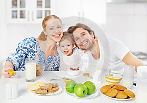 Happy family mother, father, child baby daughter having breakfast