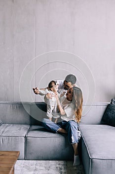 Happy family mother, father, child baby daughter at home on the sofa playing