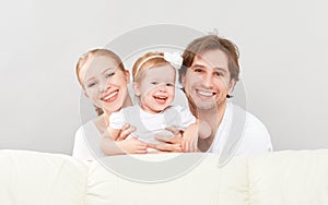 Happy family mother, father, child baby daughter at home on sofa playing and laughing