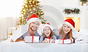 Happy family mother father and child on Christmas morning in bed
