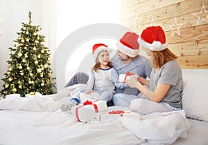 Happy family mother father and child on Christmas morning in bed