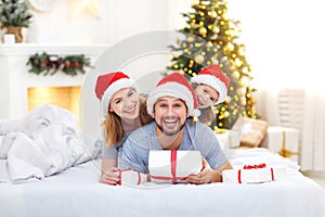 Happy family mother father and child on Christmas morning in bed