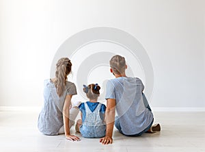 Happy family mother, father and child daughter   backs on blank grey wall