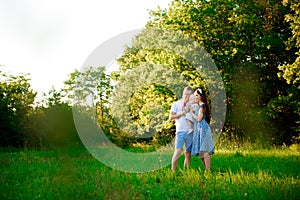 Happy family: mother father and child daughter in the park on sunset