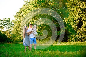 Happy family: mother father and child daughter in the park on sunset