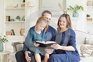 Happy family. Mother, father and child daughter reading a book