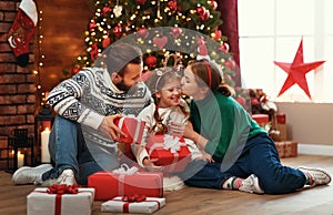 Happy family mother, father and child  with gifts near   Christmas tree at home
