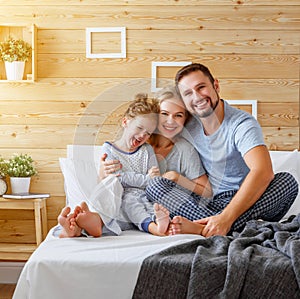 Happy family mother, father and child laughs in bed