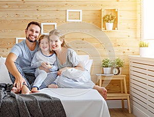 Happy family mother, father and child laughs in bed