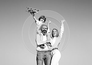 Happy family mother father and child on sky nature. Parents with child. Boy with toy airplane on fathers shoulders