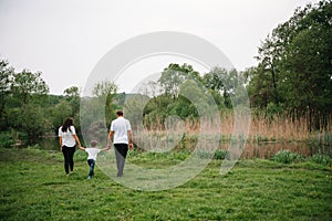 Happy family: mother father and child son on nature on sunset. Mom, Dad and kid laughing and hugging, enjoying nature outside.