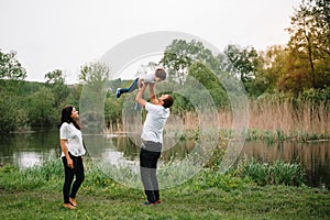 Happy family: mother father and child son on nature on sunset. Mom, Dad and kid laughing and hugging, enjoying nature outside.