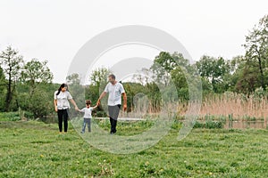 Happy family: mother father and child son on nature on sunset. Mom, Dad and kid laughing and hugging, enjoying nature outside.