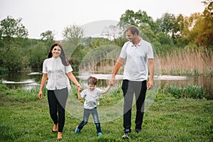 Happy family: mother father and child son on nature on sunset. Mom, Dad and kid laughing and hugging, enjoying nature outside.