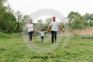 Happy family: mother father and child son on nature on sunset. Mom, Dad and kid laughing and hugging, enjoying nature outside.