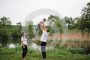 Happy family: mother father and child son on nature on sunset. Mom, Dad and kid laughing and hugging, enjoying nature outside.