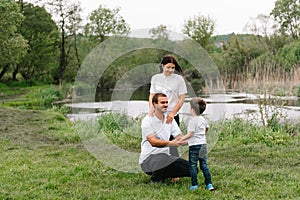 Happy family: mother father and child son on nature on sunset. Mom, Dad and kid laughing and hugging, enjoying nature outside.