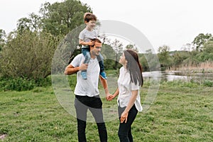 Happy family: mother father and child son on nature on sunset. Mom, Dad and kid laughing and hugging, enjoying nature outside.