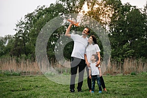 Happy family: mother father and child son on nature on sunset. Mom, Dad and kid laughing and hugging, enjoying nature