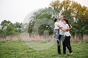 Happy family: mother father and child son on nature on sunset. Mom, Dad and kid laughing and hugging, enjoying nature