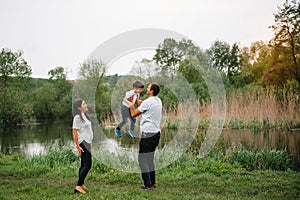 Happy family: mother father and child son on nature on sunset. Mom, Dad and kid laughing and hugging, enjoying nature outside.