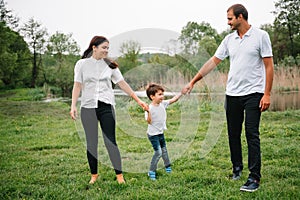 Happy family: mother father and child son on nature on sunset. Mom, Dad and kid laughing and hugging, enjoying nature outside.