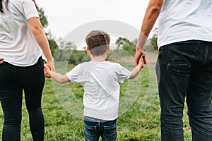 Happy family: mother father and child son on nature on sunset. Mom, Dad and kid laughing and hugging, enjoying nature outside.