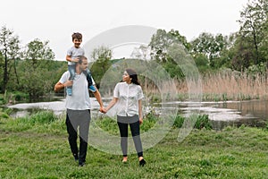 Happy family: mother father and child son on nature on sunset. Mom, Dad and kid laughing and hugging, enjoying nature outside.