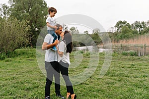 Happy family: mother father and child son on nature on sunset. Mom, Dad and kid laughing and hugging, enjoying nature outside.