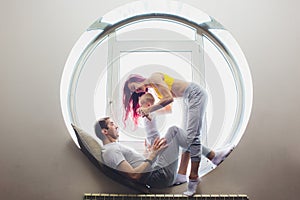 happy family of mother, father and child son playing and cuddling at home on floor near a big window.