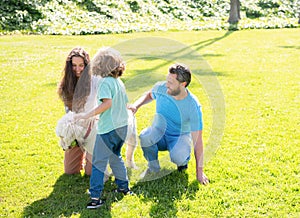 happy family of mother father and child son playing with pet dog in summer park green grass, fun