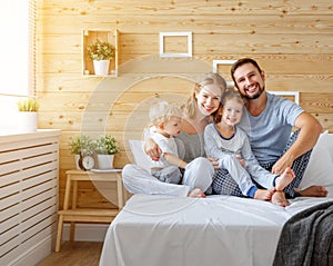 Happy family mother father and children daughter and son in bed