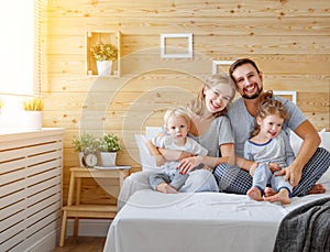 Happy family mother father and children daughter and son in bed