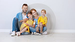 Happy family mother father and children daughter and son  near an empty   blank wall