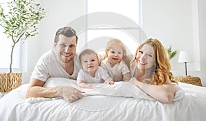 happy family mother, father and children having fun in bed in bedroom at home