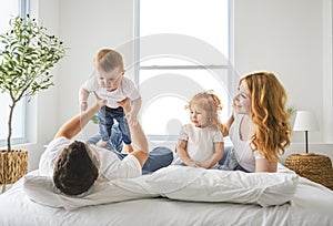 happy family mother, father and children having fun in bed in bedroom at home