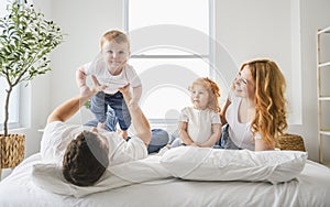 happy family mother, father and children having fun in bed in bedroom at home