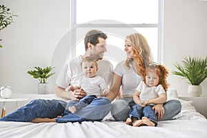 happy family mother, father and children having fun in bed in bedroom at home