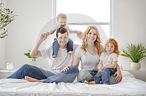 happy family mother, father and children having fun in bed in bedroom at home