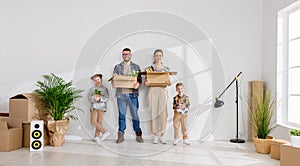 Happy family mother father and children move to new apartment and stand in a row with boxes in their hands against an empty wall