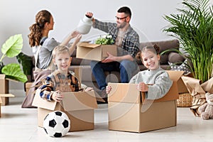 Happy family mother father and children move to new apartment and unpack boxes