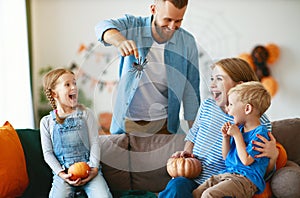 Happy  family mother father and children prepare for Halloween decorate  home with pumpkins and  laughing, play and scare  with