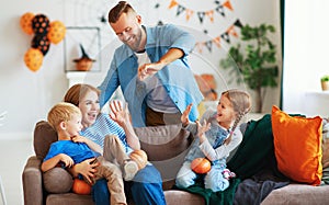 Happy  family mother father and children prepare for Halloween decorate  home with pumpkins and  laughing, play and scare  with