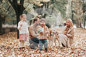 Happy family: mother, father, children son, daughter and dog labrador walking and have fun in park. Warm memories. Relations Love