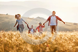 Happy family: mother, father, children son and daughter runing and jumping on sunset