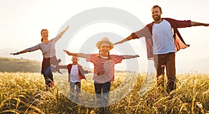 Happy family: mother, father, children son and daughter runing and jumping on sunset